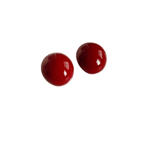 Glossy red spherical stud earrings with silver needles on a clean white background