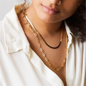 Close-up of layered golden snake chain and paperclip link necklace on a model