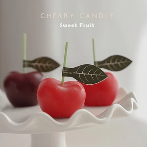 Velas aromáticas realistas con forma de cereza en rojo y granate con hojas verdes
