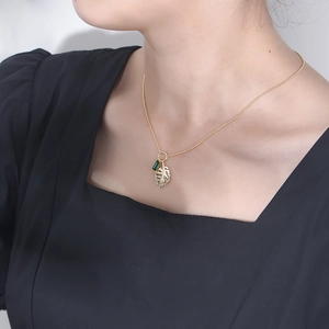 Macro detail of 925 silver gold-plated necklace with emerald zircon and leaf pendant