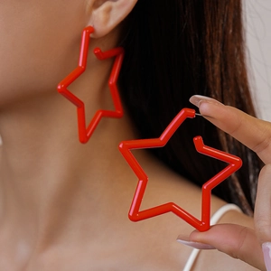 Gros plan d'un mannequin portant de grandes boucles d'oreilles étoiles rouges en acrylique