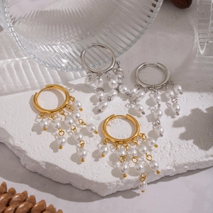 Elegant gold and silver tassel pearl earrings displayed on a white textured stone base
