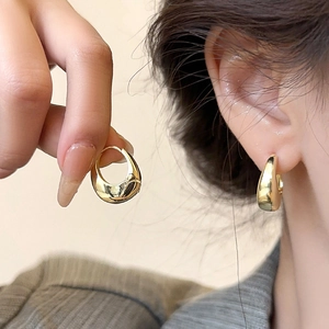Close-up of polished gold teardrop earrings showing elegant curvature and metallic shine
