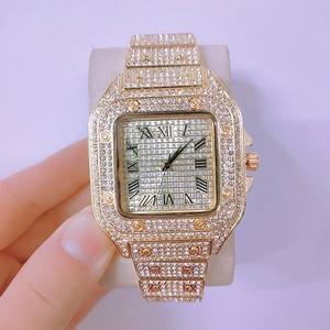 Detail shot of a square gold watch with sparkling diamonds and Roman numeral markers