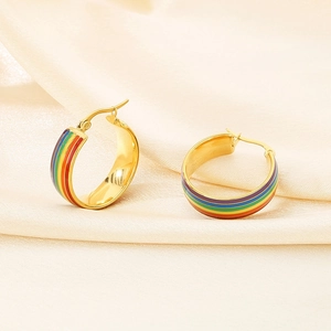 Detailaufnahme von Regenbogen Emaille Creolen auf elegantem Seidenstoff Hintergrund