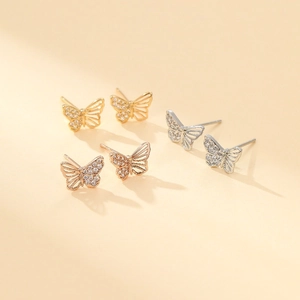 Detailed macro shot of three butterfly stud earrings with zircon inlay in gold and silver
