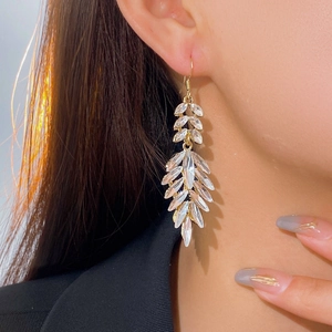 Side view of long gold leaf drop earrings with crystals worn by a female model