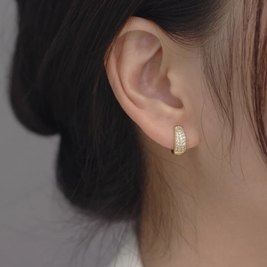 Macro view of gold plated huggie earrings with shimmering pavé micro-inlaid zircon stones