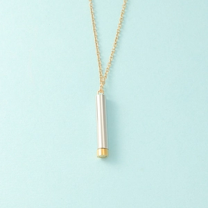 Detail of two-tone cylindrical pendant with silver body, gold base, and gold chain necklace