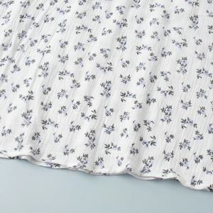 Detail of floral printed cotton fabric showing white crepe texture and purple blossom pattern
