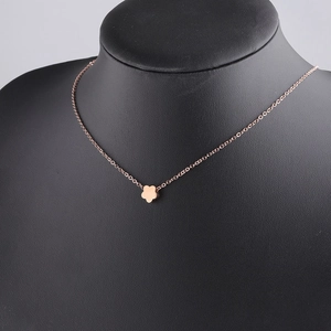 Macro view of rose gold flower pendant and delicate chain on a black bust mannequin