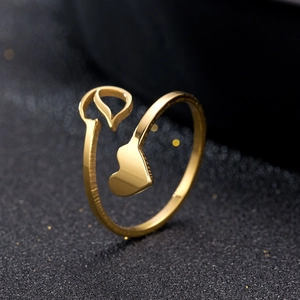 Close-up of golden heart-shaped stainless steel open ring on a dark textured background