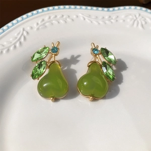 Macro view of pear-shaped green gemstone earrings with gold leaves and blue accents