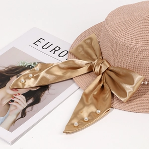Detail of elegant straw hat with oversized pink satin bow and pearl accents for summer