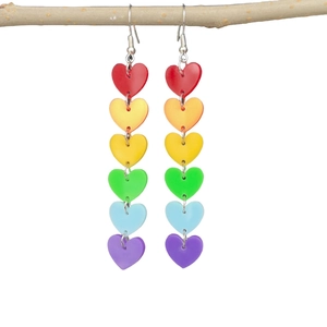 Detailed shot of rainbow heart tassel earrings in acrylic hanging on a natural wood branch