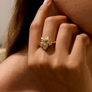 Minimalist two-tone 18K gold and stainless steel flower ring worn on a finger