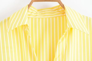 Detail of yellow and white striped shirt collar on a wooden hanger with precise stitching
