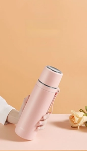 Close-up of pink stainless steel vacuum flask with handy carrying strap and sleek matte finish