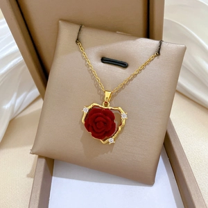 Detail of gold heart pendant with red velvet rose and white zircon in a jewelry box