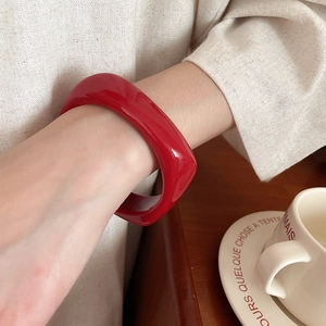 Close-up of a glossy red square resin bangle worn on a wrist for a retro fashion look
