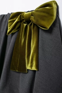 Gros plan d'un nœud en velours sur une jupe vert armée avec texture riche et brillance