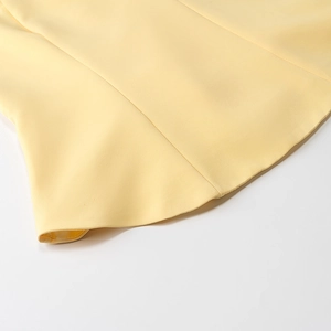 Vue détaillée de l'ourlet en tissu plissé jaune et finition des coutures soignée