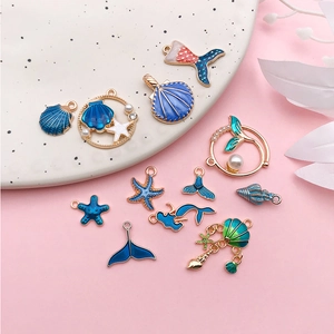 Macro shot of 12 ocean-themed enamel charms including shells, starfish and mermaid tails