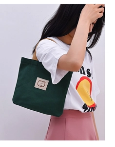Close-up of green canvas tote bag featuring cute bear patch and love embroidery