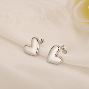 Detailed macro view of heart-shaped stainless steel earrings on elegant silk fabric
