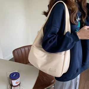 Detailansicht einer großen beigen PU-Leder-Schultertasche in Halbmondform mit breitem Gurt
