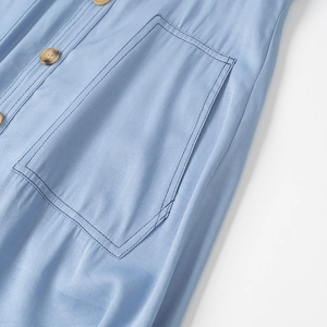 Primo piano di una gonna blu stile denim che mostra la grande tasca laterale e i bottoni