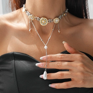 Detail of layered baroque necklace with gold sun pendant and drop pearl on model