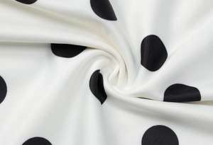 Dettaglio del tessuto bianco a pois neri che mostra la texture morbida e le pieghe