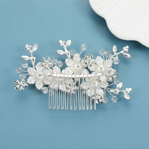 Detail of bridal hair comb featuring white resin flowers and silver metal wire leaves