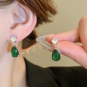 Close-up of green teardrop cubic zirconia earrings with silver claw setting detail