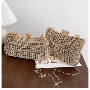 Detailed view of two gold evening clutch bags featuring full rhinestone and metal chains