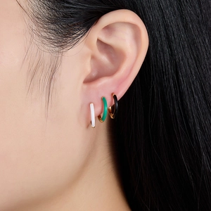 Three minimalist S925 silver hoop earrings in white, green, and black on model