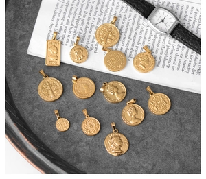 Close-up of vintage Roman coin pendants in 18K gold-plated steel on a dark tray