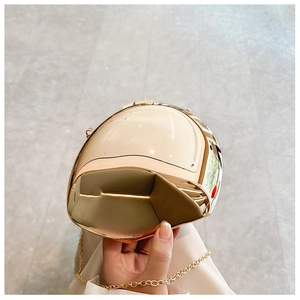 Close-up of egg-shaped creative helmet evening bag with acrylic champagne gold finish