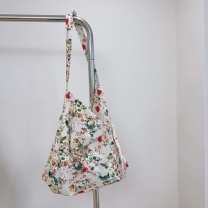 Close-up of floral cotton hobo bag with colorful patterns hanging on a metal rack