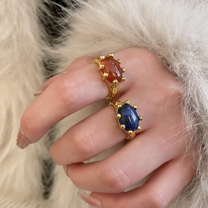 Detailed close-up of vintage gold plated rings with red agate and blue lapis lazuli stones