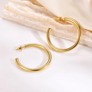 Minimalist C-shaped thick hoop earrings in gold plated stainless steel on silk background
