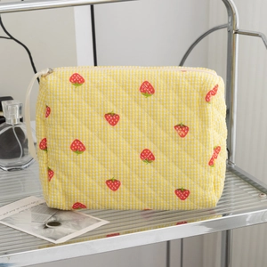 Detailed texture of quilted cotton cosmetic bag with yellow gingham and strawberry prints