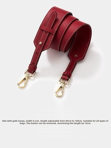 Detail of red leather wide shoulder strap with contrast stitching and gold buckle