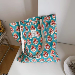 Detail showing the vintage floral print and brand label on a teal cotton tote bag