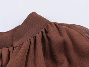 Close-up of ruffled shoulder and pleated neckline texture on brown bohemian maxi dress