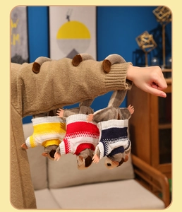 Close-up of three plush monkey pendants in colorful striped sweaters hanging on an arm