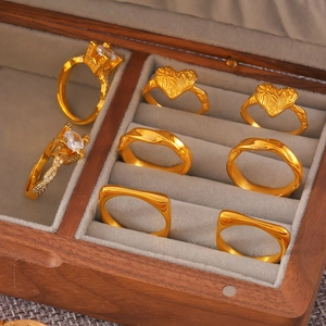 Bagues géométriques dorées avec zircons et motif cœur dans une boîte à bijoux en bois