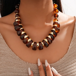 Close-up of amber acrylic irregular beads and golden rings on an ethnic sweater necklace