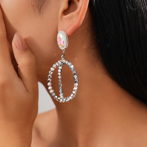 Close-up of model wearing silver oval hoop earrings with rainbow crystal and beaded fringe